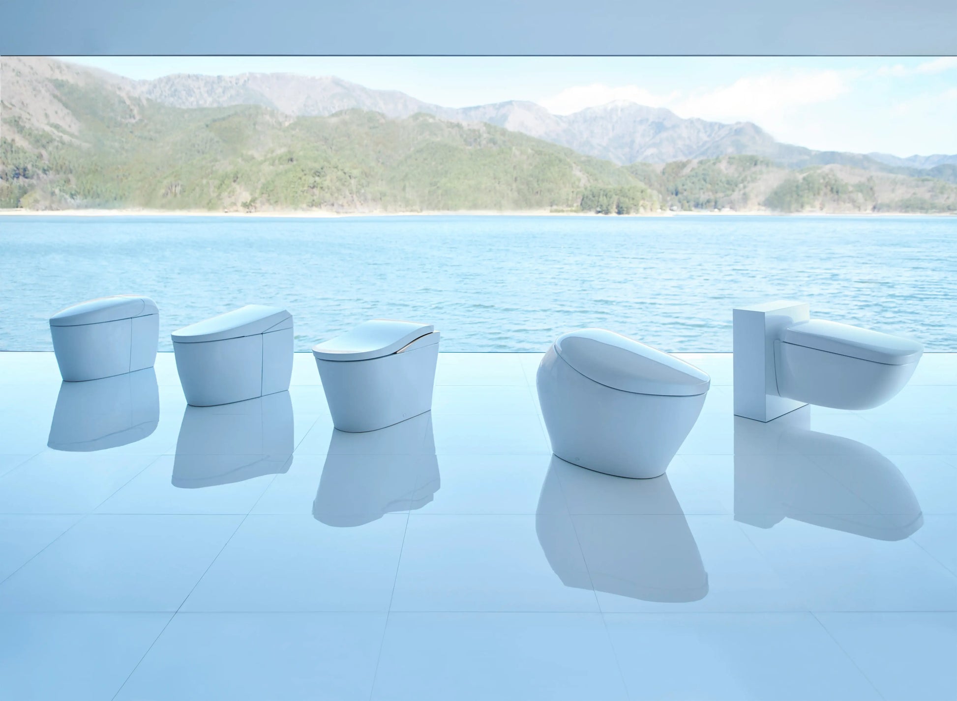 Row of TOTO NEOREST integrated bidet toilets displayed beside an infinity pool with a mountain backdrop